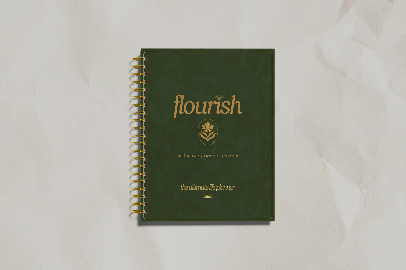 The Flourish planner cover, deep green with gold foil, on white paper