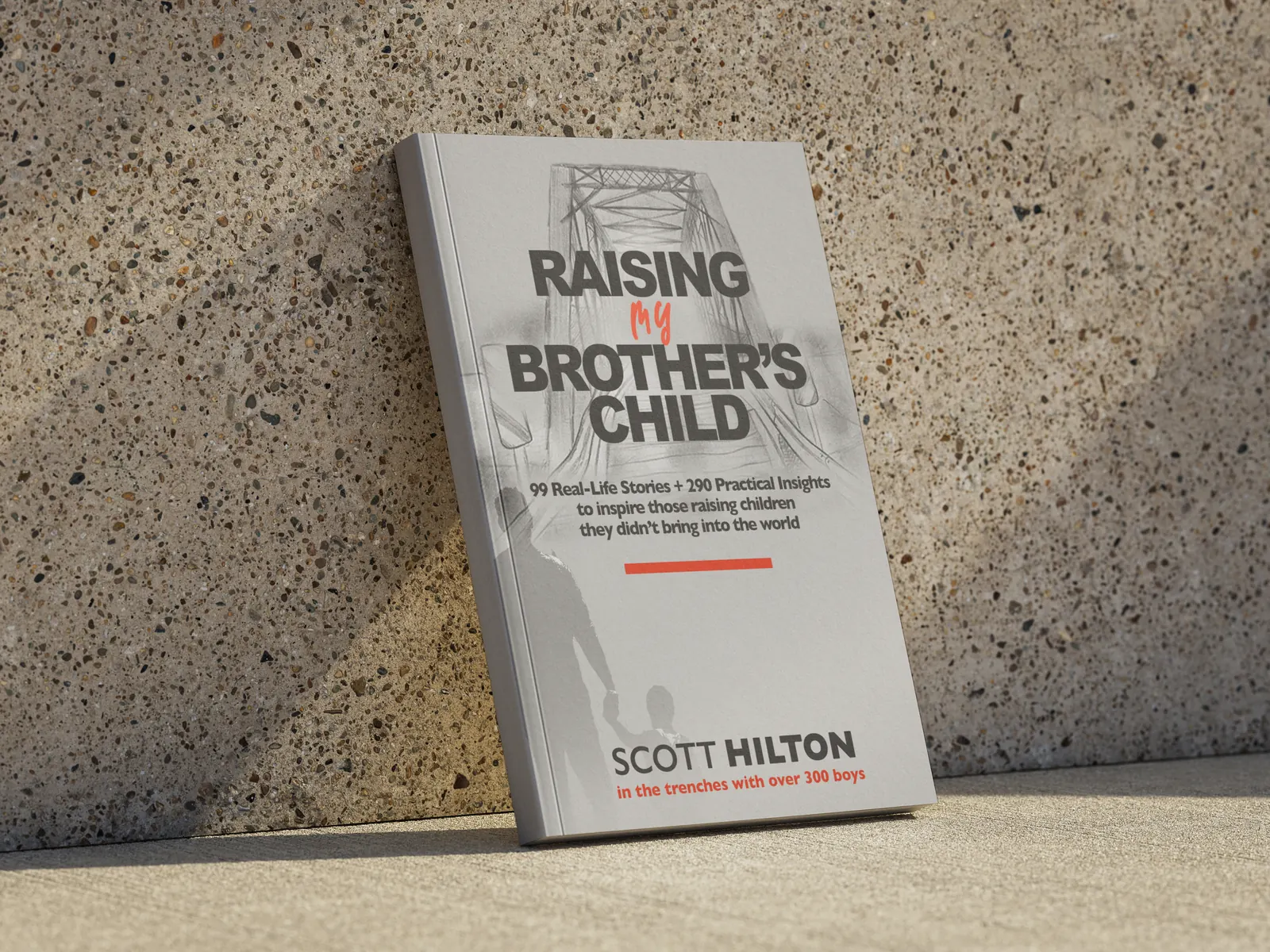 Raising My Brother's Child by Scott Hilton, a light gray paperback leaning on a stone wall