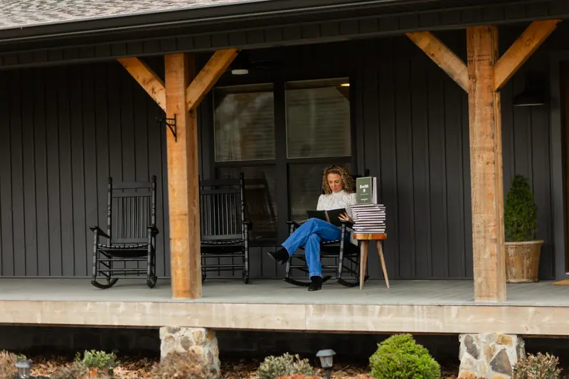 Michelle Johnson reading Flourish in a rocking chair on a dark wooden porch