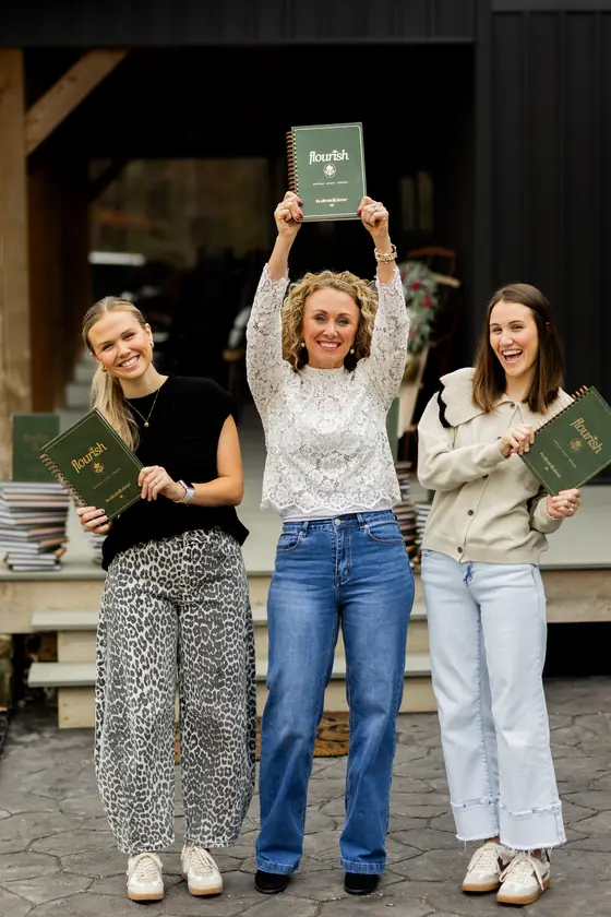 Three women holding up copies of the Flourish planner