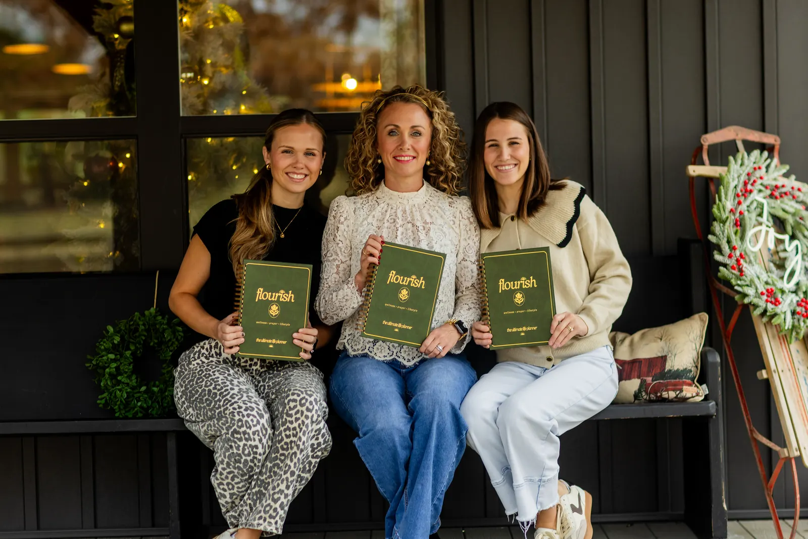 Michelle Johnson and two friends on a porch bench, each holding a Flourish planner