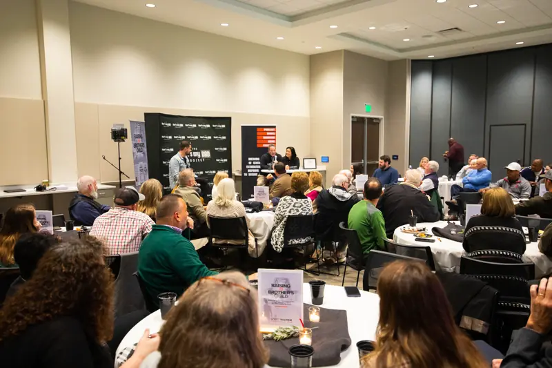 A full room of guests at round tables during the launch of Raising My Brother's Child